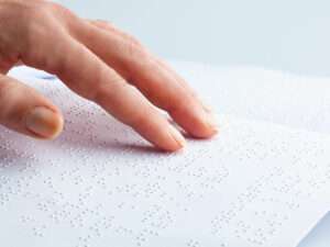 Finger tasten sich über Braille-Schrift