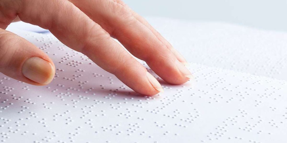 Finger tasten sich über Braille-Schrift
